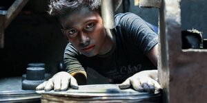 Ein Junge arbeitet an einer Drehscheibe und hat Farbe im gesicht