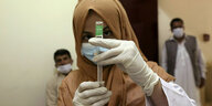 Eine Ärztin mit Kopftuch zieht eine Spritze für eine Impfung auf