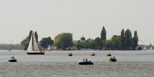 Segelboote und Schlauchboote schwimmen im Wasser des Steinhuder Meeres, im Hintergrund ist die Insel Wilhelmstein zu erkennen.