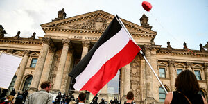 Eine Reichsfahne (Schwarz Weiß Rot) wird vor dem Deutchen Bundestag geschwenkt.