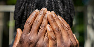 Schwarzer Mensch bedeckt das Gesicht mit den Händen