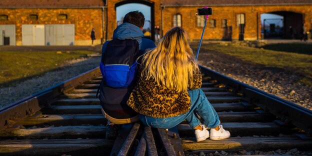 Paar macht ein Selfie auf den Gleisen der KZ-Gedenkstätte Auschwitz-Birkenau.