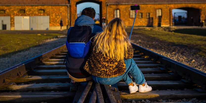 Paar macht ein Selfie auf den Gleisen der KZ-Gedenkstätte Auschwitz-Birkenau.