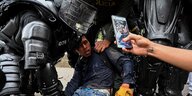Polizisten nehmen einen jungen Demonstranten fest, ein Handy filmt es