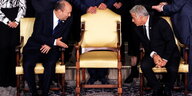 Bennett und Lapid sitzen jeweils links und rechts von einem gold gepolsterten Stuhl und gucken sich über den Stuhl hinweg an. Sie wirken höflich formal, Bennett macht eine einladende Handbewegung