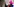 Eine junge Frau mit schwarzen langen Haaren und einer pinken Mütze berührt mit der Hand die Rinde eines Baumes