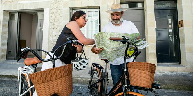 Zwei touristen auf Fahrrädern schauen auf eine Landkarte