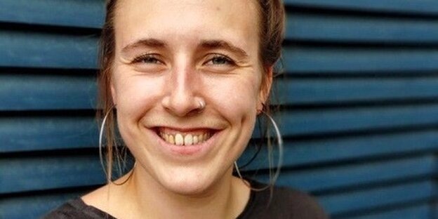 Eine junge Frau mit Creolohrringen lächelt in die Kamera