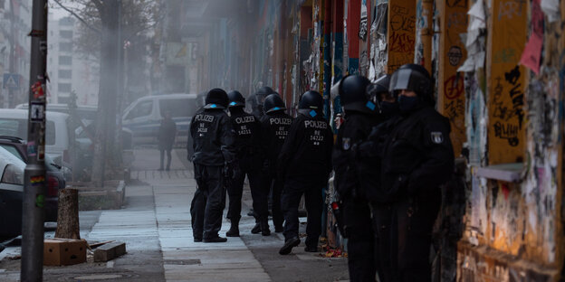 Polizisten stehen an der Hauswand neben der Rigaer 94