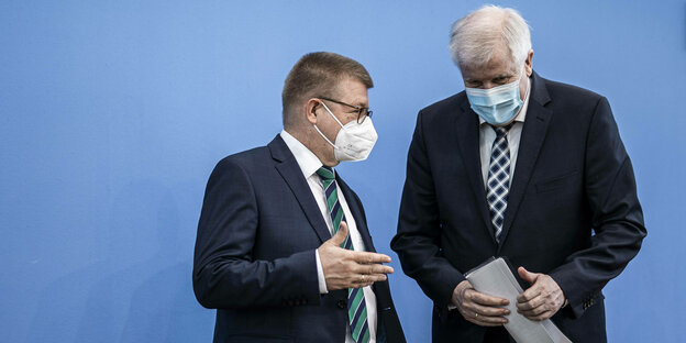 Innenminister Seehofer steht dicht neben Thomas Heldenwang, dem Verfassungsschutz-Präsidenten, beide mit Mund-Nasen-Schutz, Haldenwang spricht