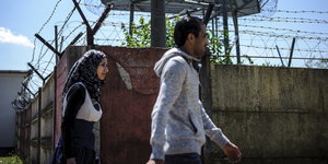 Zwei Flüchtlinge laufen an einer Mauer entlang