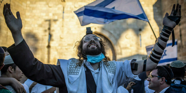 Ein ultra-orthodoxer Jude gestikuliert - hinter ihm eine Israel Flagge