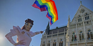 Eine Drag Queen schwenkt die Regenbogenflagge vor dem Parlamentsgebäude in Budapats