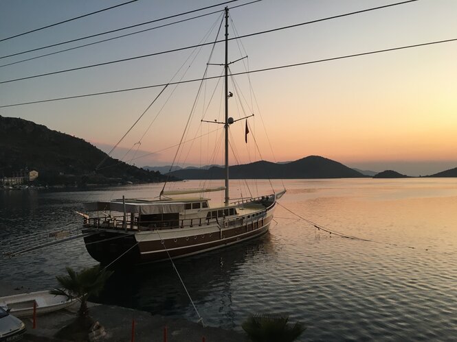 Ein traditionell aus Holz gefertigtes Gulet - Segelboot im Sonnenuntergang im Meer