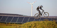 Mountainbikefahrer auf Mountainbike Arena vor Solarpark und Windrad