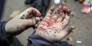 Mit Sekundenkleber und Glitter verschmiert ein Aktivist seine Hände