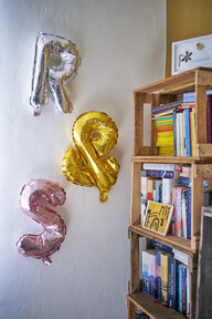 Neben einem Bücherregal hängen an der Wand Luftballons in Form von R & S Neben einem Bücherregal hängen an der Wand Luftballons in Form von R & S