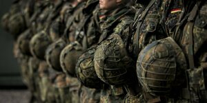 Eine Gruppe von Soldaten steht in einer Reihe, die Helme vor ihrer Brust