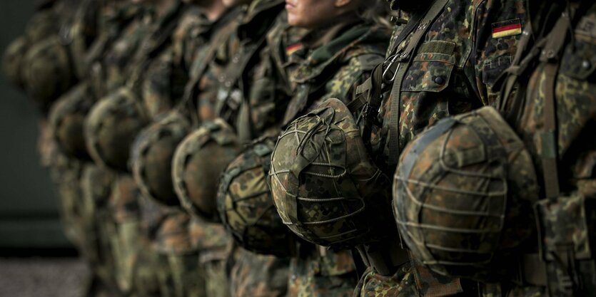 Eine Gruppe von Soldaten steht in einer Reihe, die Helme vor ihrer Brust