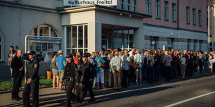 Bürger stehen vor einem Haus Schlange