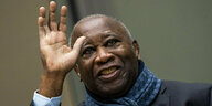 Ehemaliger Präsident der Elfenbeinküste Laurent Gbagbo trägt Schal und grüßt mit seiner Hand