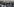 In schwarz gekleidete Demonstrierende mit Schildern und Polizisten mit Schutzhelmen