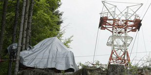 Das Wrack der abgestürzten Seilbahn neben dem Mast - abgedeckt unter einer Plane