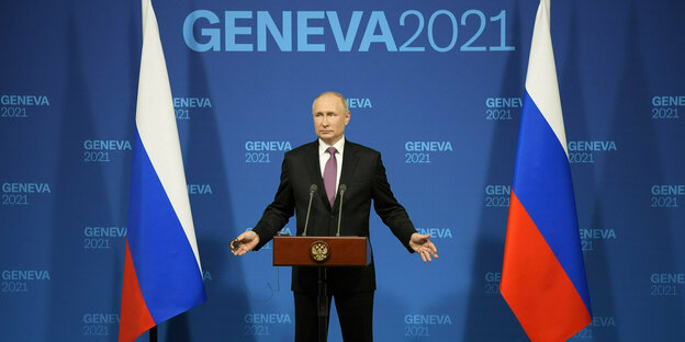 Wladimir Putin spricht auf einer Pressekonferenz an einem Pult - neben ihm russische Flaggen