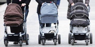 Drei Kinderwagen werden einen Weg heruntergeschoben