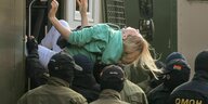 Eine Frau wird von Soldaten gewaltvoll in einen Transporter verfrachtet