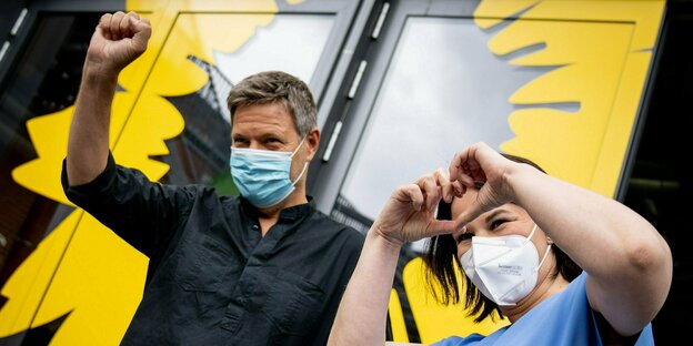 Robert Habeck und Annalena Baerbock mit Mundschutz vor einer Tür mit aufgemalter gelber Sonnenblume