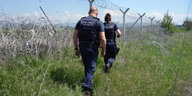 Deutsche Polizisten patrouillieren an einem stacheldrahtbewehrten Grenzzaun in Griechenland