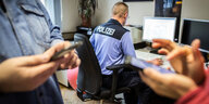 Auf einer Polizeiwache sitzt ein Polizist am Bildschirm seines Computers