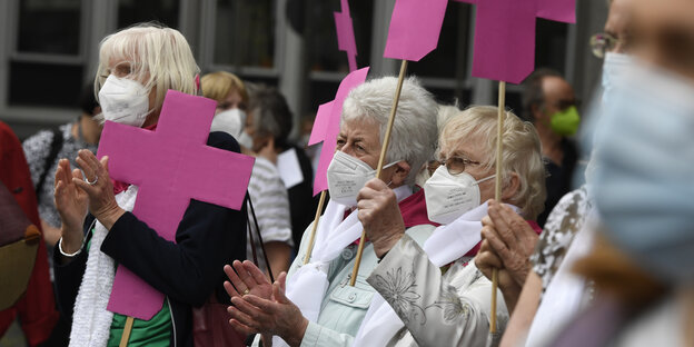 Protestierende vor Woelkis Wohnhaus fordern mit pinken Pappkreuzen Aufklärung der Missbrauchsfälle