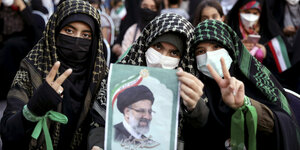 Drei junge Anhängerinnen mit Schleier und Kopftuch halten das Bild des künftigen iranischen Präsidenten Raisi. Eine der Frauen signalisiert mit V den Sieg.