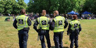 Polizisten auf einer Wiese vor Demonstranten der "Querdenken"-Bewegung