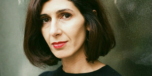 Die Autorin Nava Ebrahimi steht vor einer Glaswand und blickt direkt in die Kamera