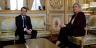 Macron und Le Pen sitzen im Elysee-Palast und lächeln in die Kamera