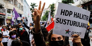 Eine junge Frau mit Victoryzeichen, in der anderen Hand hält sie ein Plakat für die HDP