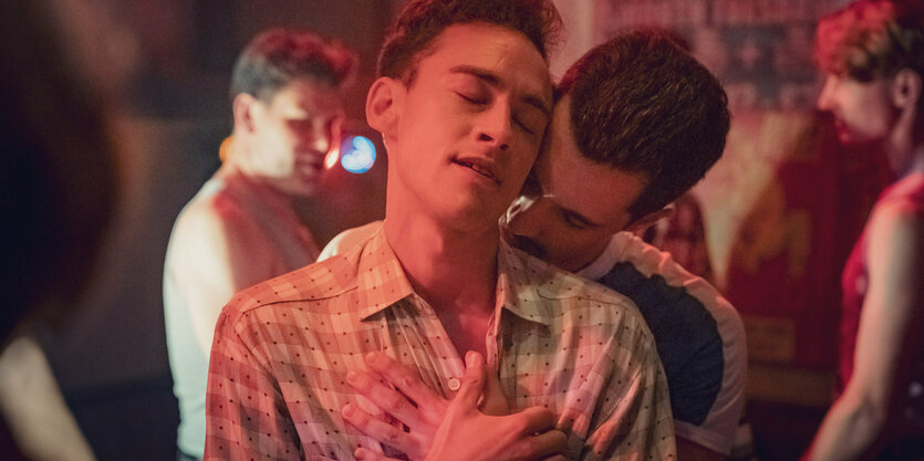 Olly Alexander (l) als Ritchie Tozer in einer Szene aus «It's a Sin». Die Augen hat er geschossen. Hinter ihm steht ein Mann, der seinen Kopf in den Nacken Alexanders hält.