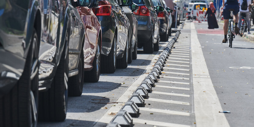 Radspur mit Protektoren neben parkenden Autos