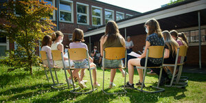 : Schülerinnen einer sechsten Klasse sitzen am letzten Schultag vor den Sommerferien im Kreis im Hof ihrer Schule zusammen