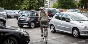 Radfahrerin bahnt sich den Weg durch parkende Autos Radfahrerin bahnt sich den Weg durch parkende Autos