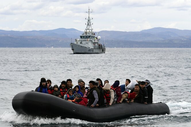 Ein Schlauchboot voller Flüchtender in den Wellen. Dahinter ein Schiff von Frontex.