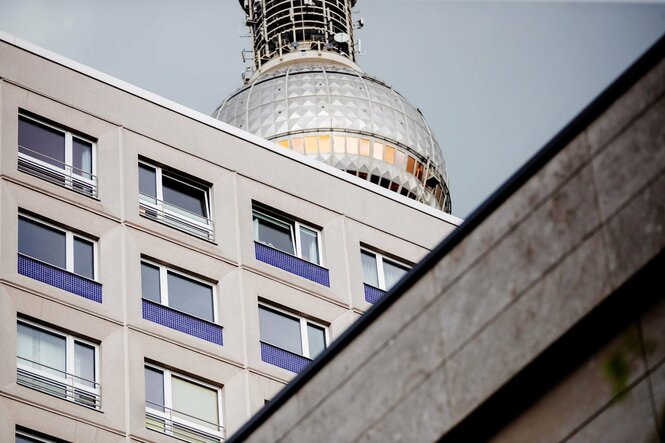 Ein Wohnhaus im Plattenstil. Direkt dahinter ist die Kugel des Fernsehturms am Berliner Alexanderplatz.