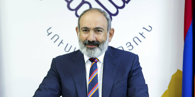 Nikol Paschinjan, Sieger der armenischen Parlamentswahl, grüßt mit erhobener Hand seine Anhänger. Er hat einen grauen Vollbart und ist von Menschen umgeben