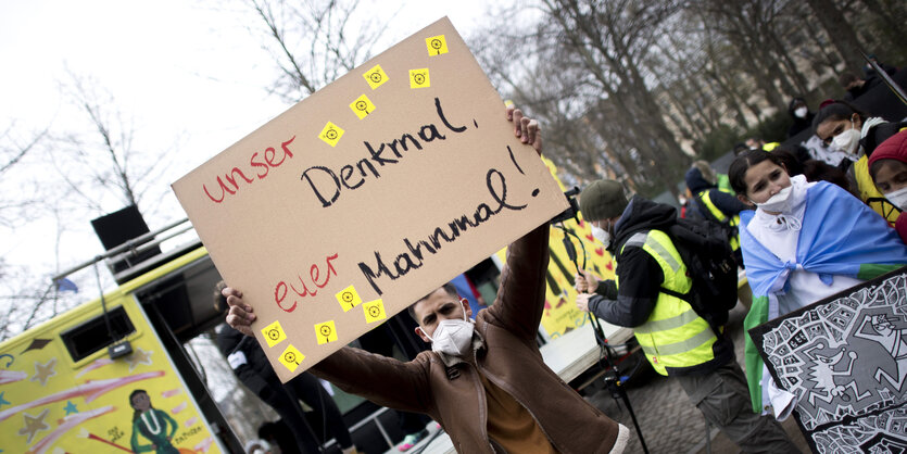 "Unser Denkmal Euer Mahnmal" steht auf eine Schild, das ein Mann hochhält