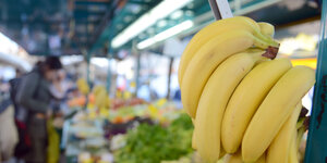Ein Wpochenmarktstand mit Obst, eine Staude Bananen im Vordergrund