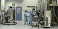 Wissenschaftler in blauen Schutanzügen in einem Labor