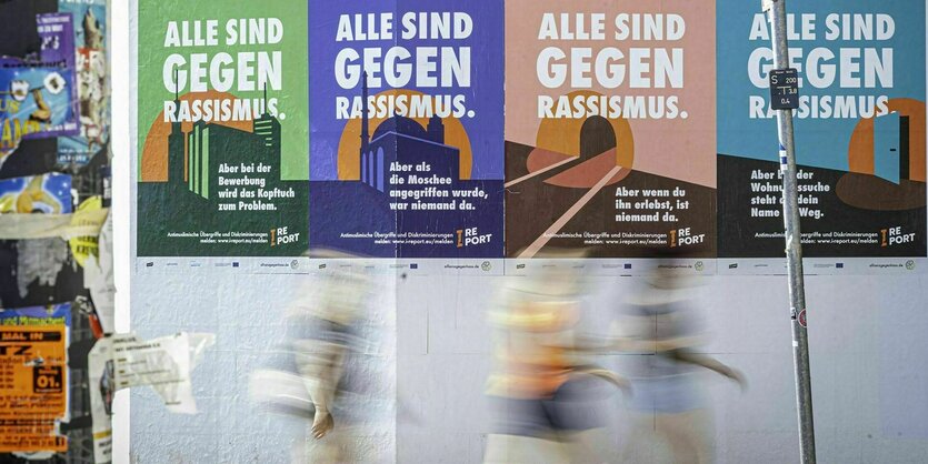 Plakate hängn an einer Wand. Darauf steht Alle gegen rassismus